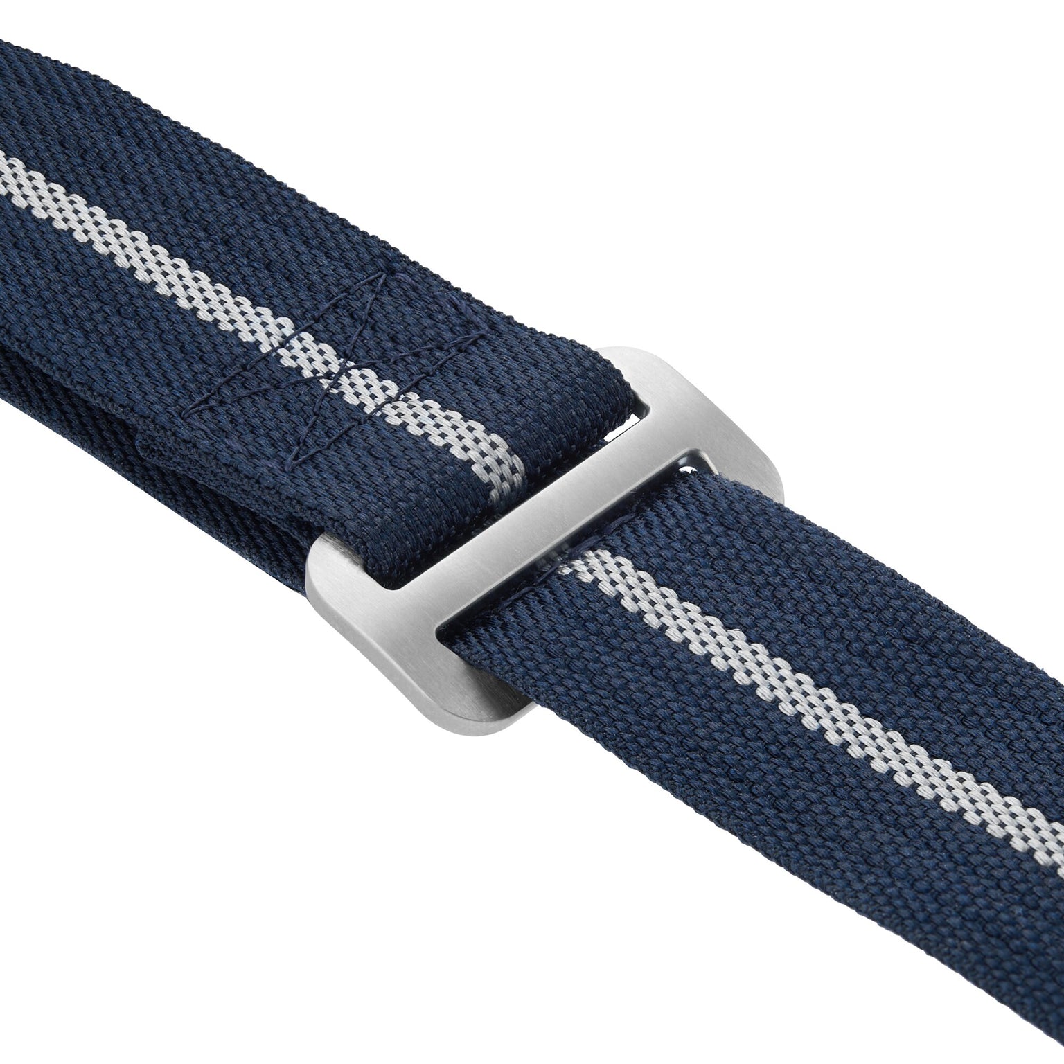 Close-up of a navy blue fabric strap with a gray metal buckle and a central white stripe, inspired by straps on the TUDOR Pelagos FXD watch.