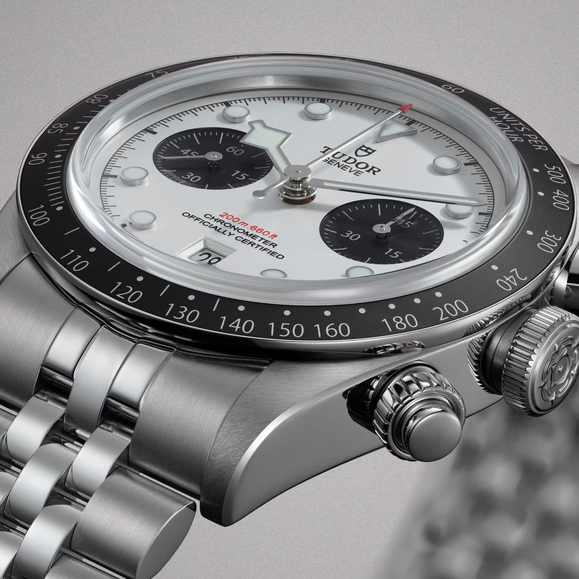 Close-up of a TUDOR Black Bay Chrono watch featuring a white dial, black bezel, and silver metal bracelet.