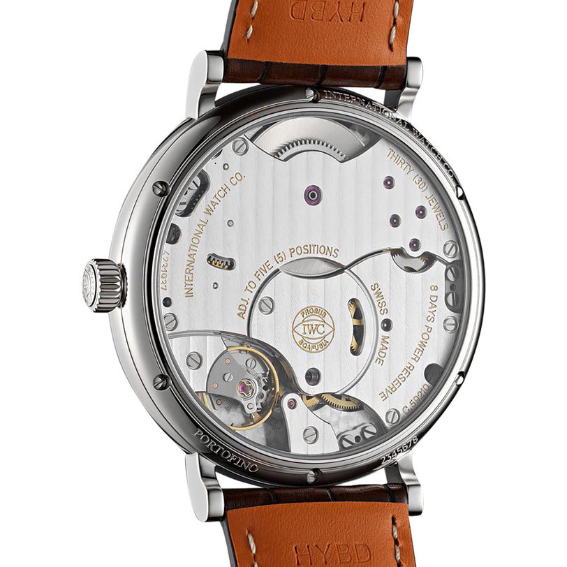 Close-up of the IWC Schaffhausen Portofino Hand-Wound Eight Days, revealing its intricate exposed gears, detailed engravings, and a brown leather strap.