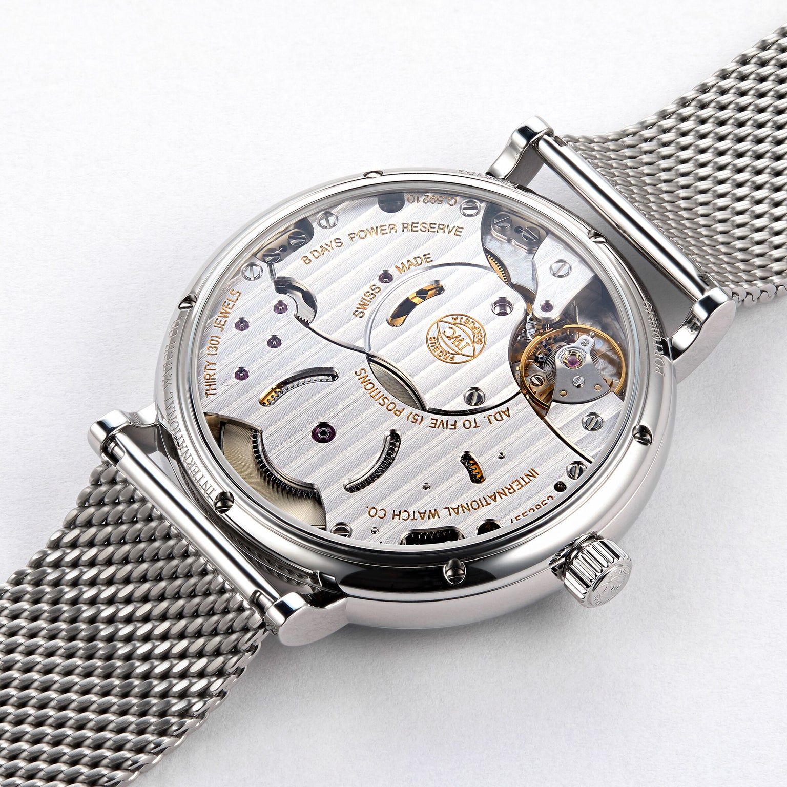 Close-up of the back of an IWC Schaffhausen Portofino Hand-Wound Eight Days watch, featuring a visible manual movement, Swiss-made inscription, and stainless steel mesh band.
