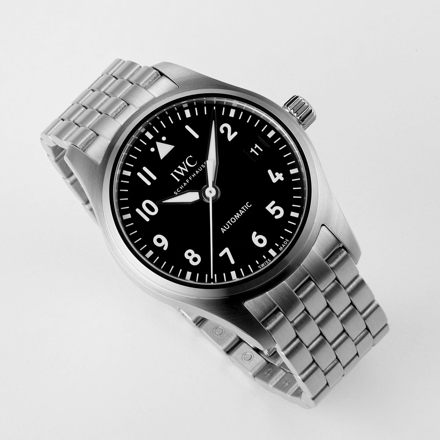 The IWC Schaffhausen Pilots Watch Automatic 36, featuring a stainless steel case, black dial with white numerals, date window, and metal link band, displays 10:09:36. Shown on a white background, it includes Caliber 35111.