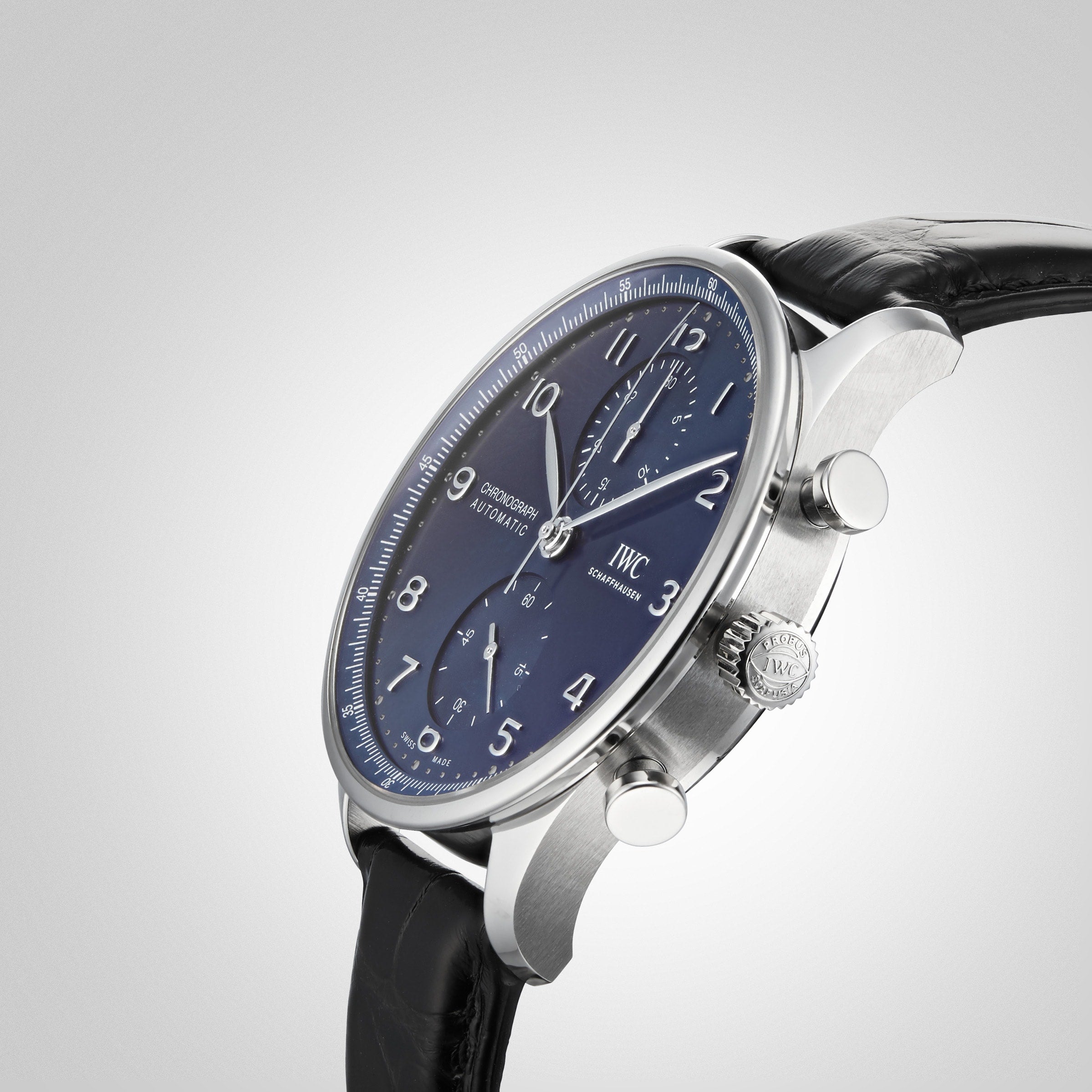 A close-up shows the IWC Schaffhausen Portugieser Chronograph with a blue dial, stainless steel case, black leather strap, and two side pushers set against a plain gray background.