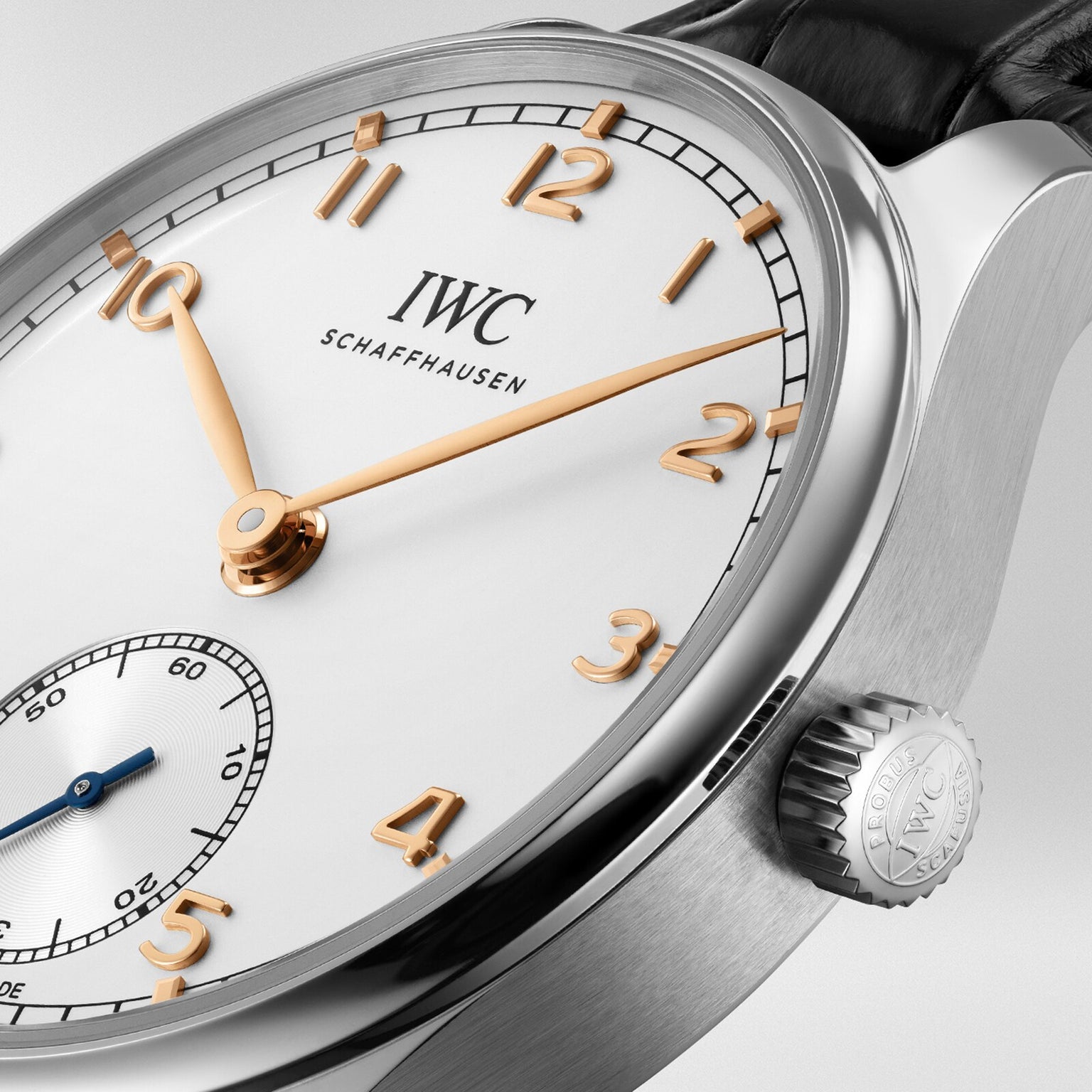 Close-up of the IWC Schaffhausen Portugieser Automatic 40 wristwatch with gold hour markers and hands, white dial, small seconds subdial, black leather strap, and IWC’s 82200 calibre featuring a Pellaton winding system.