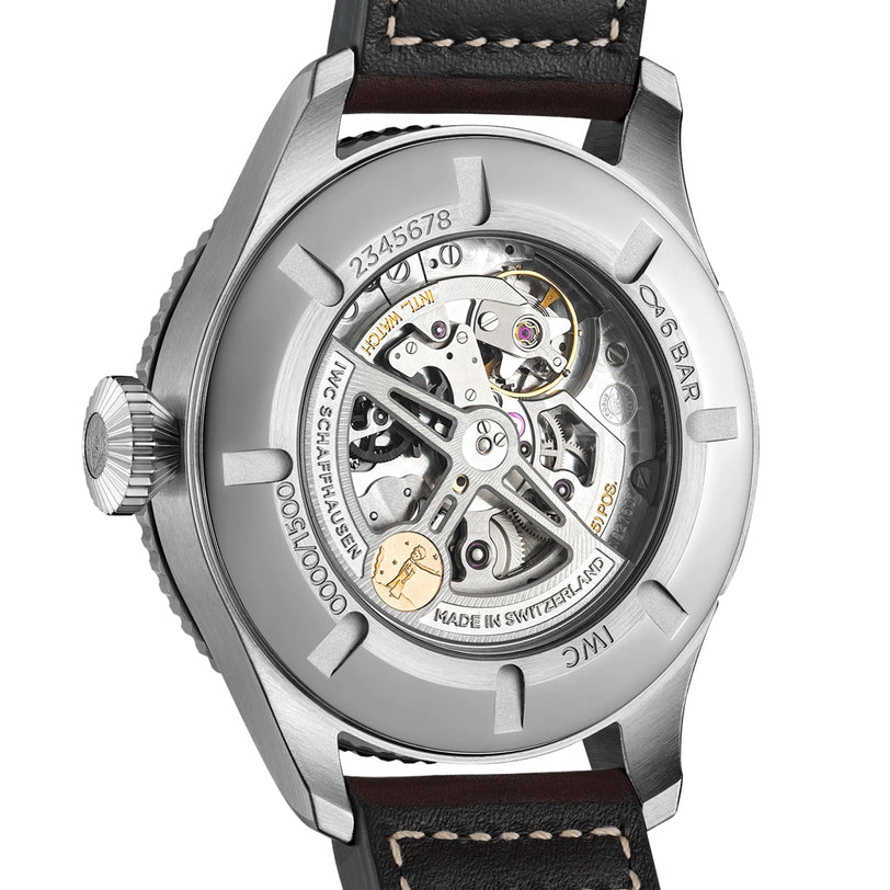 Back view of the IWC Schaffhausen Pilots Watch Timezoner Edition Le Petit Prince, featuring a stainless steel case, engraved text, a transparent case back revealing the movement, and a black leather strap.
