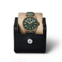 The IWC Schaffhausen Big Pilots Watch 43 Spitfire, featuring a green dial and leather strap, is displayed upright in a black textured watch case with a button closure.
