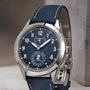 The Patek Philippe Complications 5328G-001 wristwatch features a blue textured dial and matching blue leather strap, displayed upright.