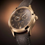 The Patek Philippe Complications 4946R-001 is a luxury wristwatch with a brown dial, gray fabric strap, and multiple subdials.