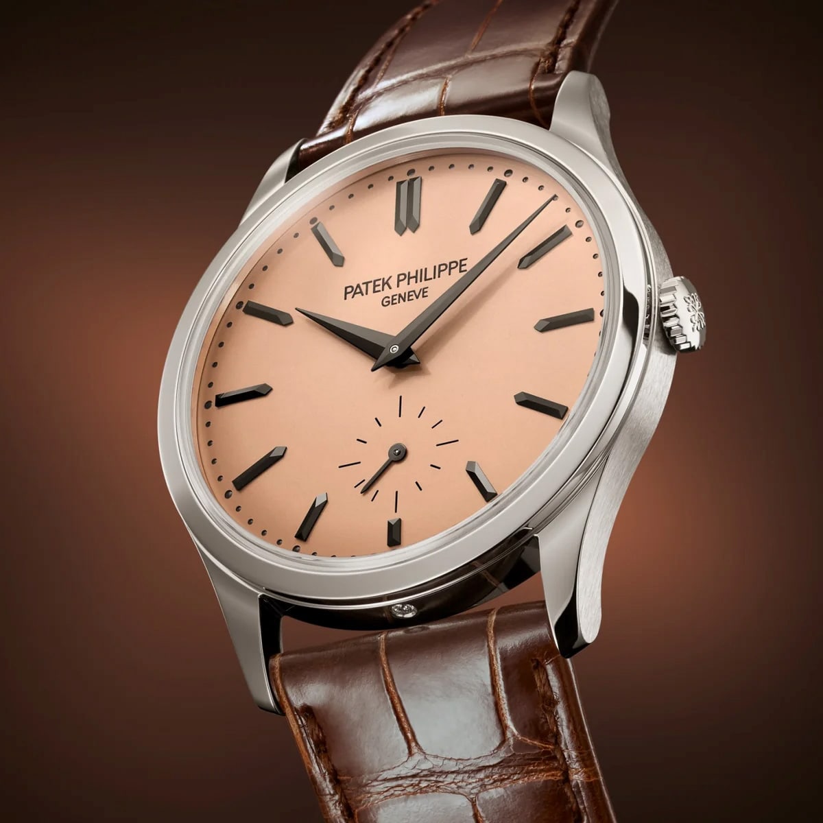 The Patek Philippe Calatrava Platinum 6196P-001 features a salmon-colored dial and brown leather strap, showcased against a brown background.