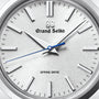 Close-up of a Grand Seiko Spring Drive Heritage watch face with silver hour markers, silver hands, and a blue second hand, displaying the time as 10:08:36.