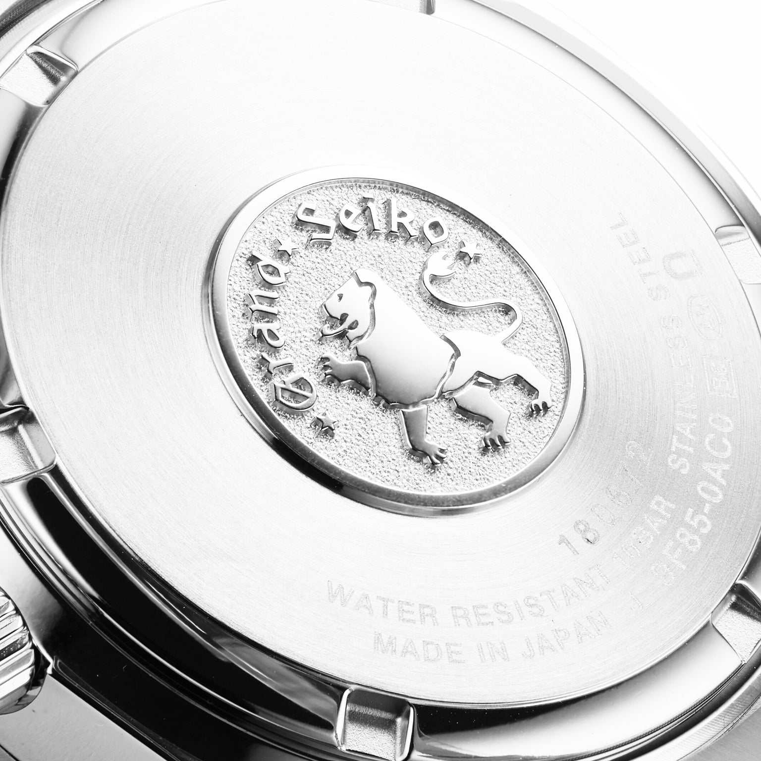 Close-up of the back of a Grand Seiko Quartz Heritage watch, featuring the engraved lion emblem, brand name, and manufacturing details on its polished stainless steel surface.