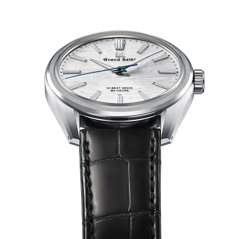 A close-up of the Grand Seiko Manual Hi-beat 80 Hours Evolution 9, featuring a textured white dial inspired by birch bark, silver hour markers, a blue second hand, and a black leather strap.