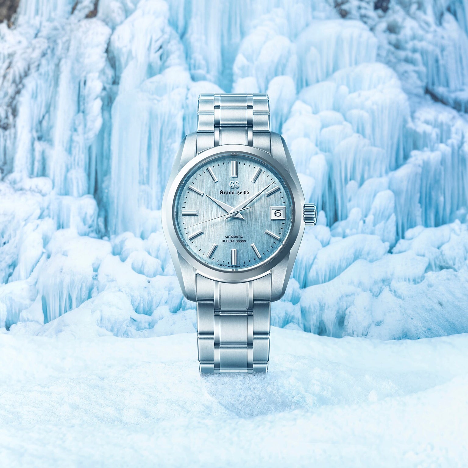 The Grand Seiko Hi-Beat Heritage watch in silver is showcased against a backdrop of blue and white ice formations.