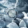 The Grand Seiko Hi-Beat Heritage, featuring a light-colored dial and date display, crafted from Ever-Brilliant Steel, rests elegantly on a bed of ice.