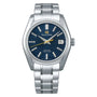 The Grand Seiko Hi-Beat Heritage is a stainless steel wristwatch with Zaratsu polishing, a blue textured dial, silver hour markers, date display at 3 o’clock, and a metal bracelet.