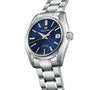 The Grand Seiko Hi-Beat Heritage is a stainless steel wristwatch with a blue textured dial, silver hour markers, date window at 3 o’clock, Zaratsu polishing, and a matching silver bracelet.