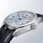 The Grand Seiko Spring Drive U.F.A Evolution 9 is a silver wristwatch featuring a textured light blue dial and a dark leather strap.