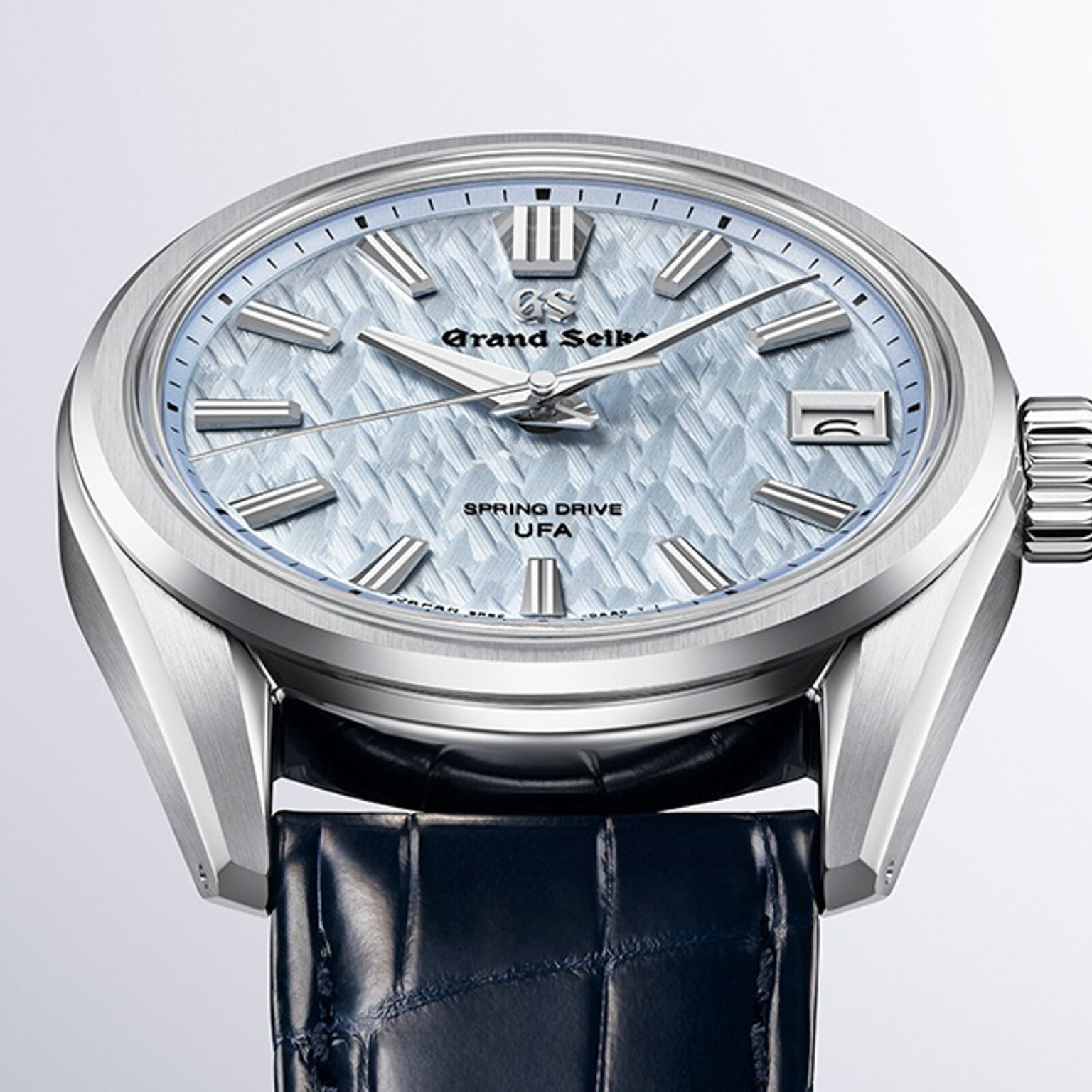Grand Seiko Spring Drive U.F.A Evolution 9 wristwatch with a light blue textured dial and dark blue leather strap, shown in close-up.