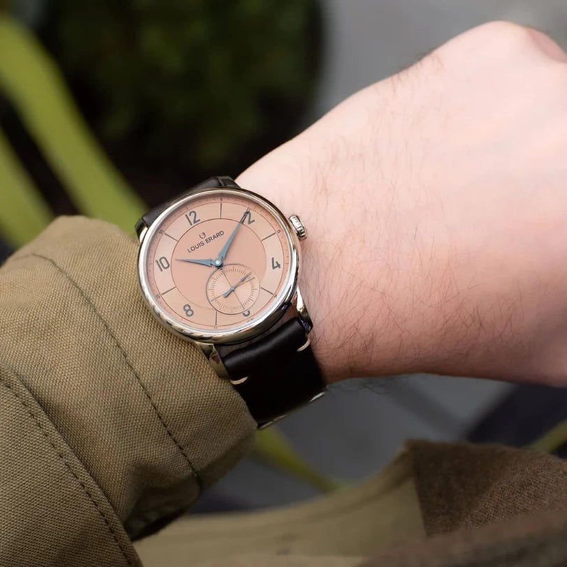 A person wearing a Louis Erard Petite Seconde Terracotta 42 wristwatch with a tan dial and black leather strap, seen from above.