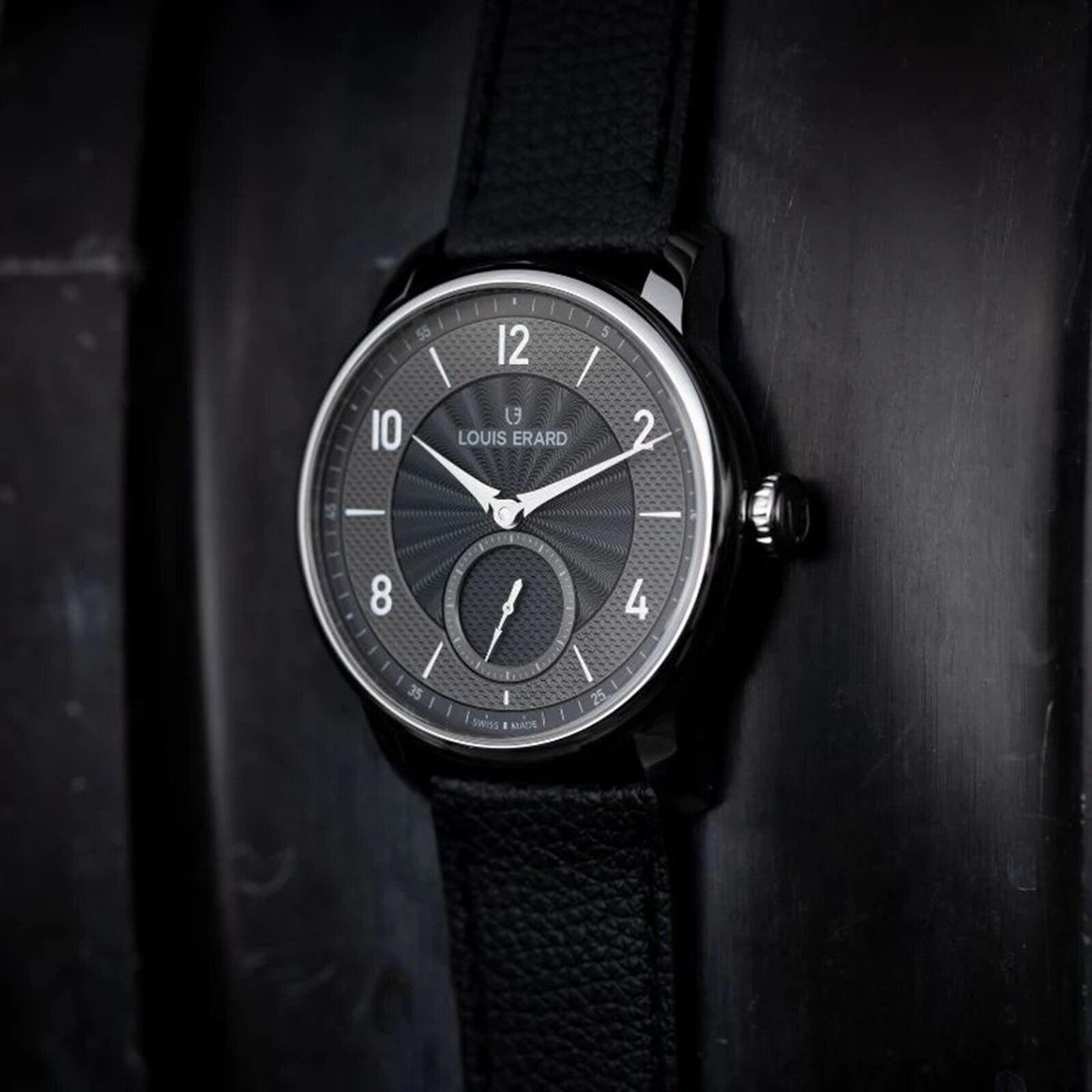 Louis Erard Petite Seconde Guilloché Anthracite Black wristwatch with a textured dial and leather strap, displayed against a dark background.
