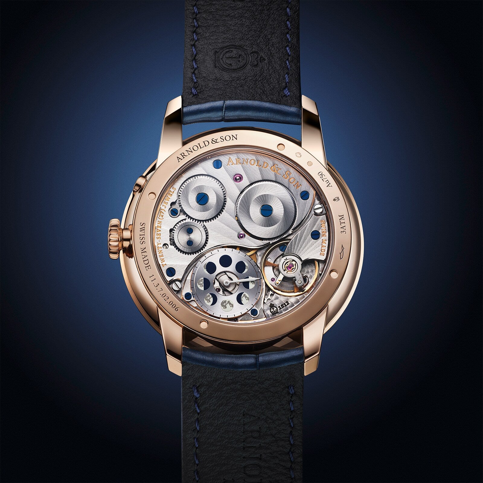 Close-up of Arnold & Son Perpetual Moon 41.5mm Red Gold’s intricate exposed movement, gold casing, and black leather strap.
