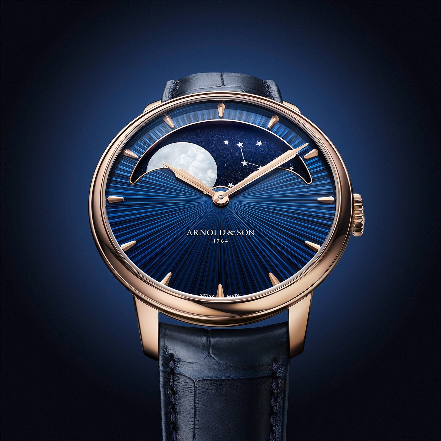 The Arnold & Son Perpetual Moon 41.5mm Red Gold features a blue starry sky dial, moon phase display, and a gold case paired with a blue leather strap.