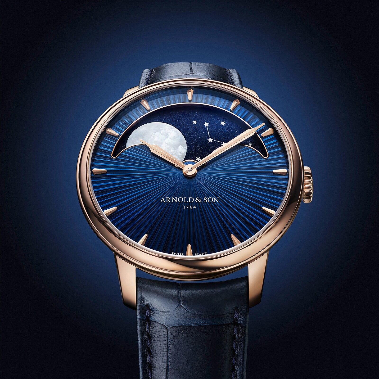 The Arnold & Son Perpetual Moon 41.5mm Red Gold features a blue starry sky dial, moon phase display, and a gold case paired with a blue leather strap.