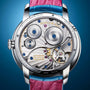 Close-up of the Arnold & Son Perpetual Moon 38 White Gold Mintnight watch back, showcasing intricate gears, engravings, and a blue and pink leather strap.
