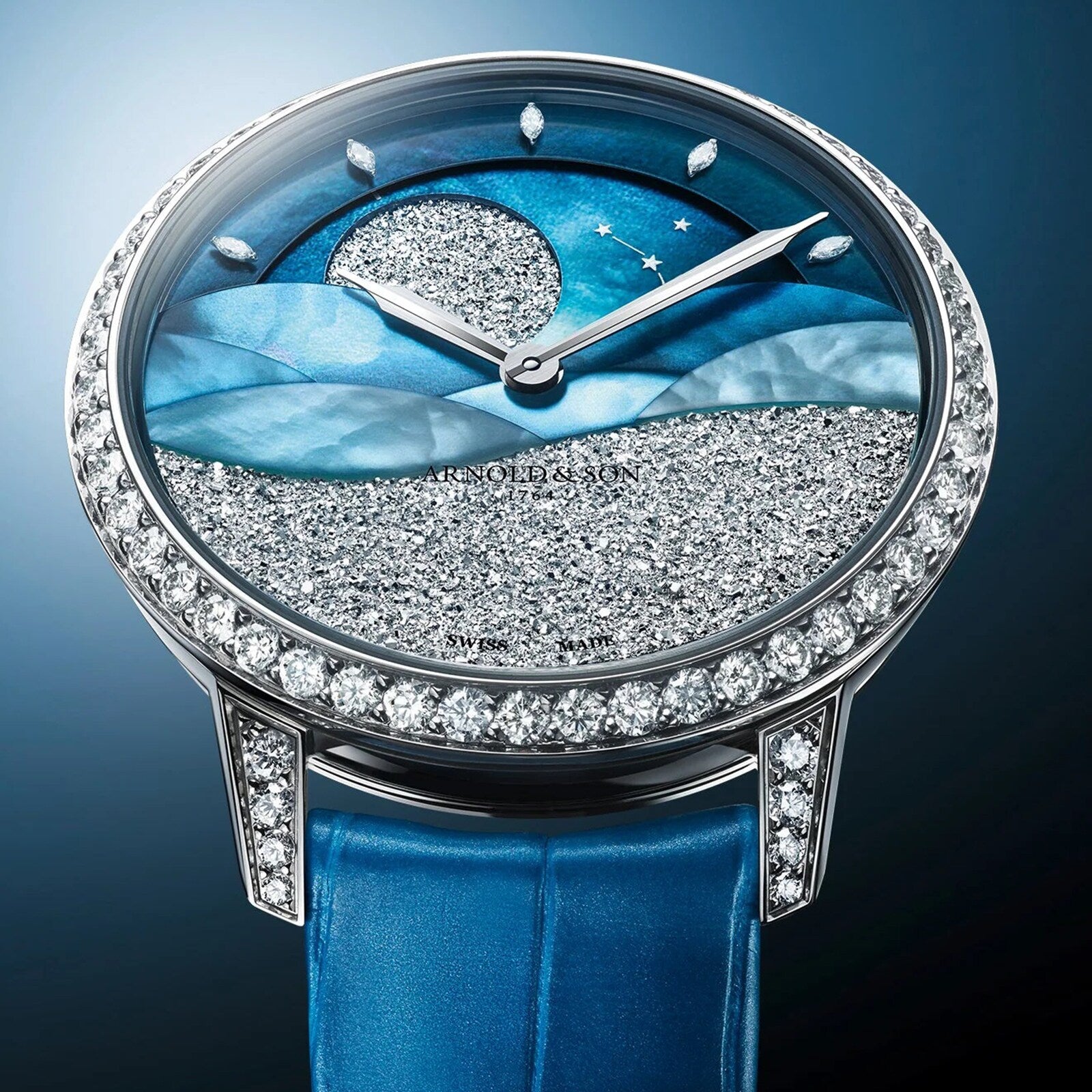 The Arnold & Son Perpetual Moon 38 White Gold Mintnight features a diamond bezel, blue strap, and a dial with a starry night sky design accented with sparkling details.