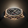 The Angelus Chronodate Gold Black is a luxury chronograph wristwatch featuring a black dial with bold numerals and a textured black strap.