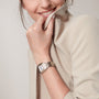 Woman wearing a silver watch on her wrist with a plain background