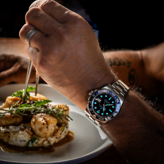 Person with a watch holding a plate of food