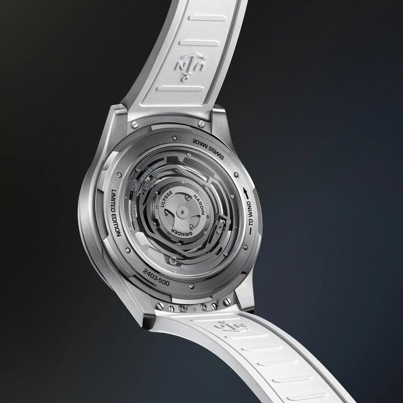 Silver titanium watch with exposed circular mechanical movement visible through case back and white strap.