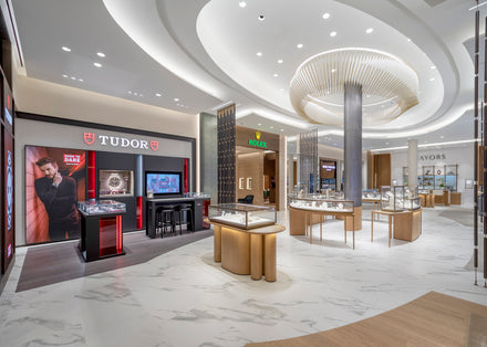 Luxury watch store interior with Tudor and Rolex displays, glass cases, and modern lighting.