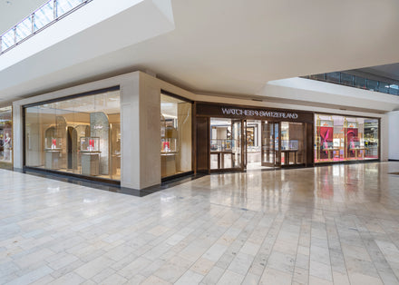 Watches of Switzerland store with glass display windows in a shopping mall, showing luxury watches inside.