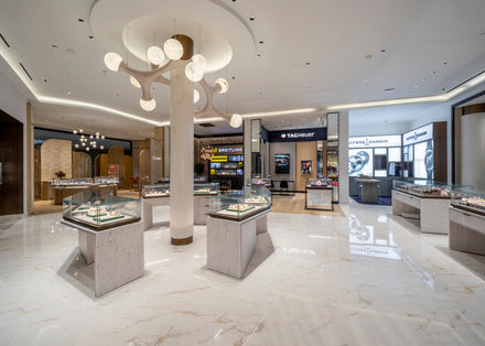Spacious, modern jewelry store with glass display cases and elegant lighting fixtures on a polished marble floor.