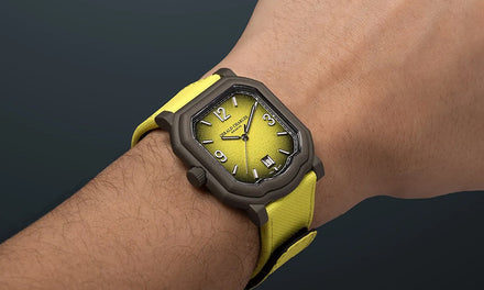 A wrist wears a Gerald Charles Maestro GC Sport watch with a bright yellow strap and a brown bezel with a brown-to-yellow gradient textured dial