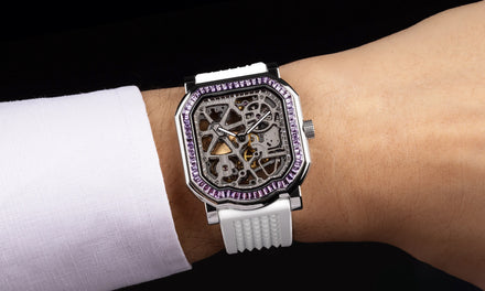 A wrist wears the Gerald Charles Maestro 8.0 Squelette watch with exposed mechanisms and a jeweled bezel and white strap