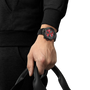 Person wearing a black watch with red accents on a white background