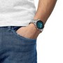 Person wearing a silver watch with a blue face on a white background