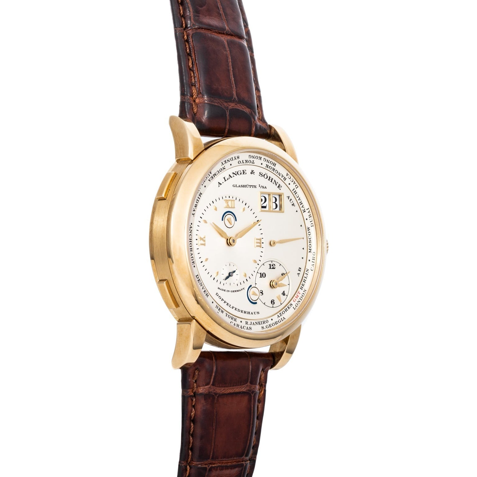 The Lange & Sohne Lange 1 Timezone is a gold luxury wristwatch with a brown leather strap and a white face featuring multiple dials and indicators.
