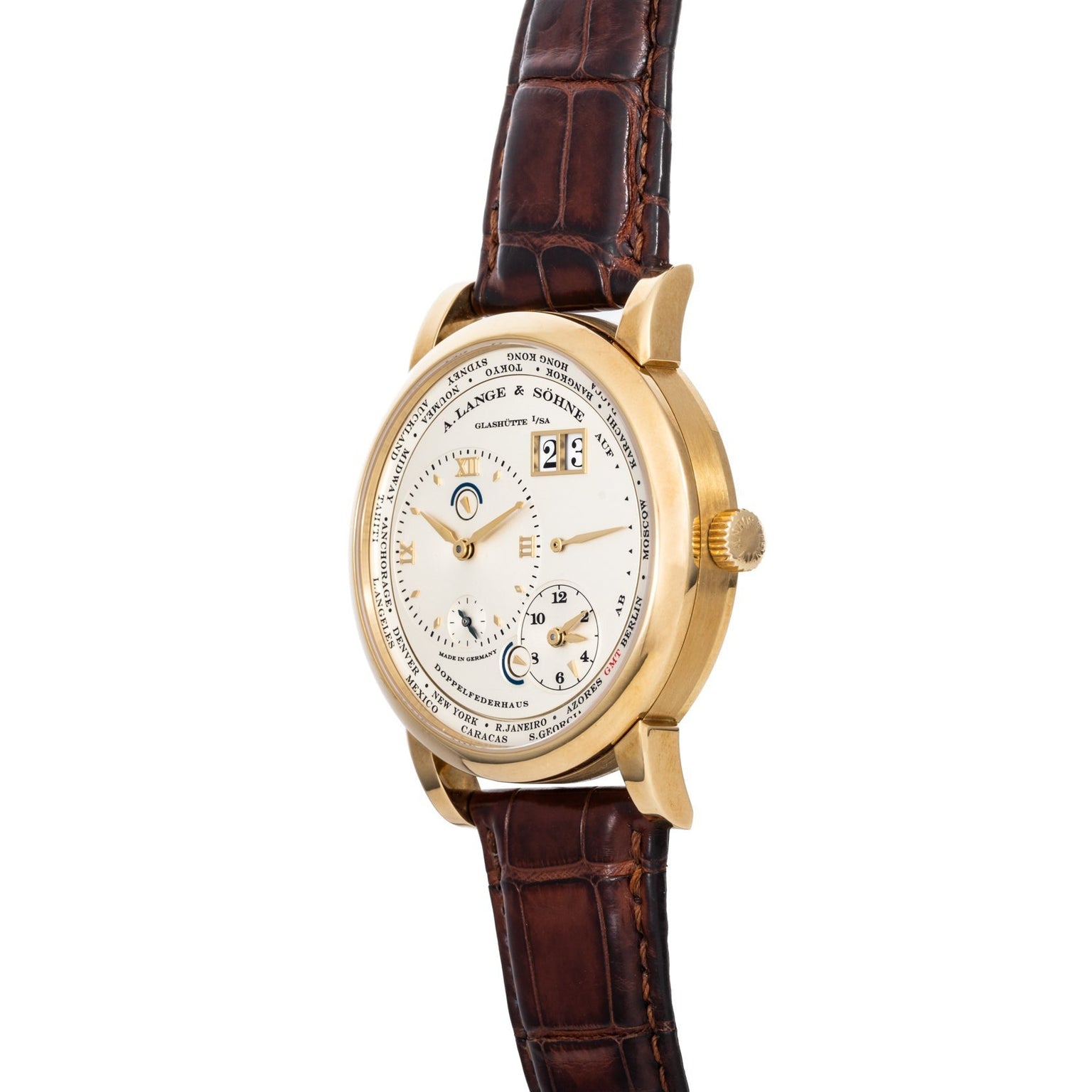 The Lange & Sohne Lange 1 Timezone features multiple dials, a gold case, brown leather strap, and a white face with black text and numbers.