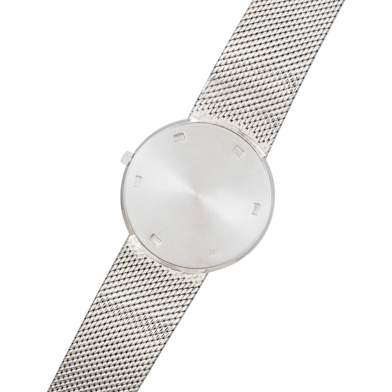 The Patek Philippe Calatrava is a minimalist silver wristwatch featuring a mesh band and a blank, unmarked watch face.