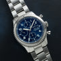 A Breitling Navitimer 8 Chronograph with a blue dial rests on a dark textured surface.