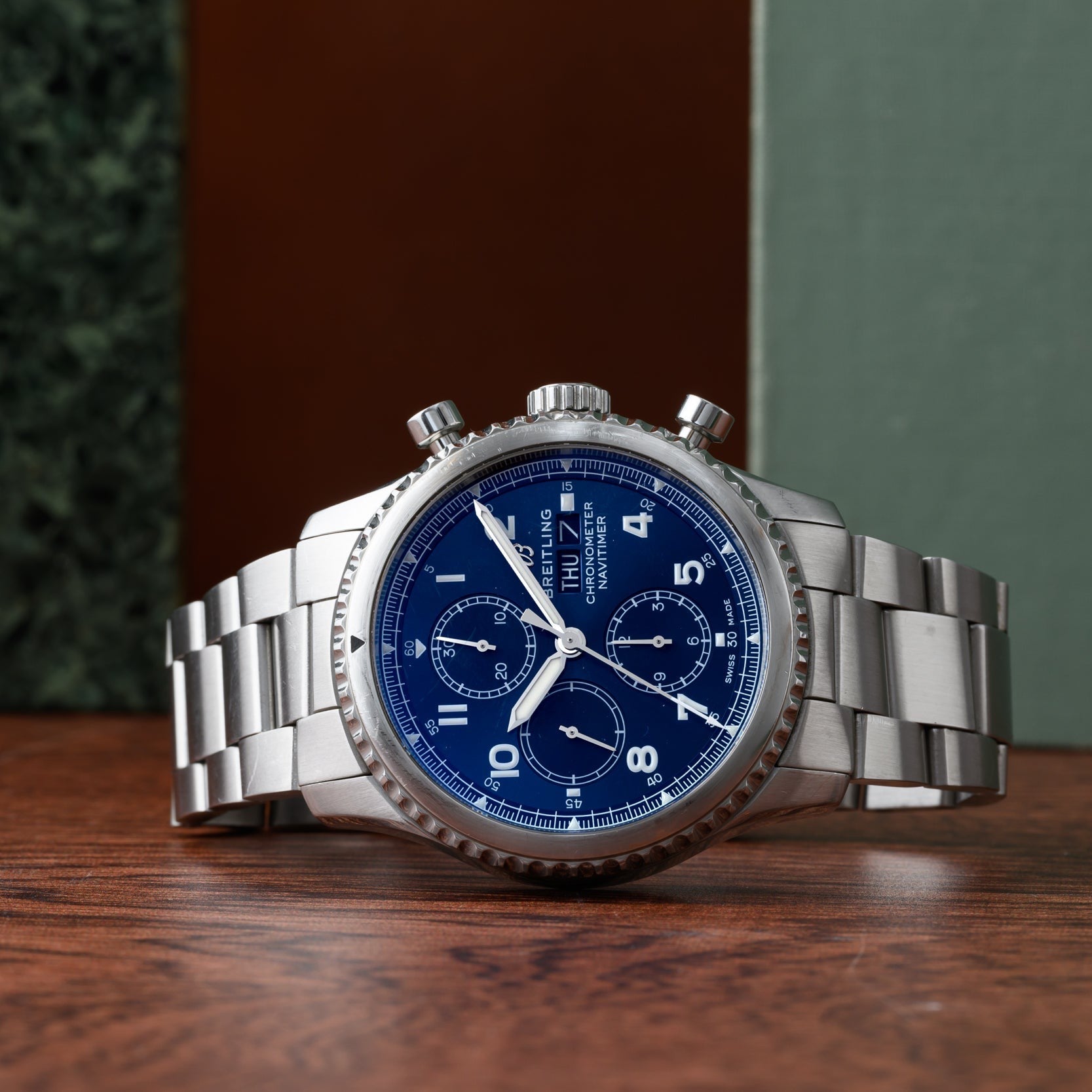 The Breitling Navitimer 8 Chronograph, featuring a blue dial and chronograph functions, is showcased on a wooden surface.