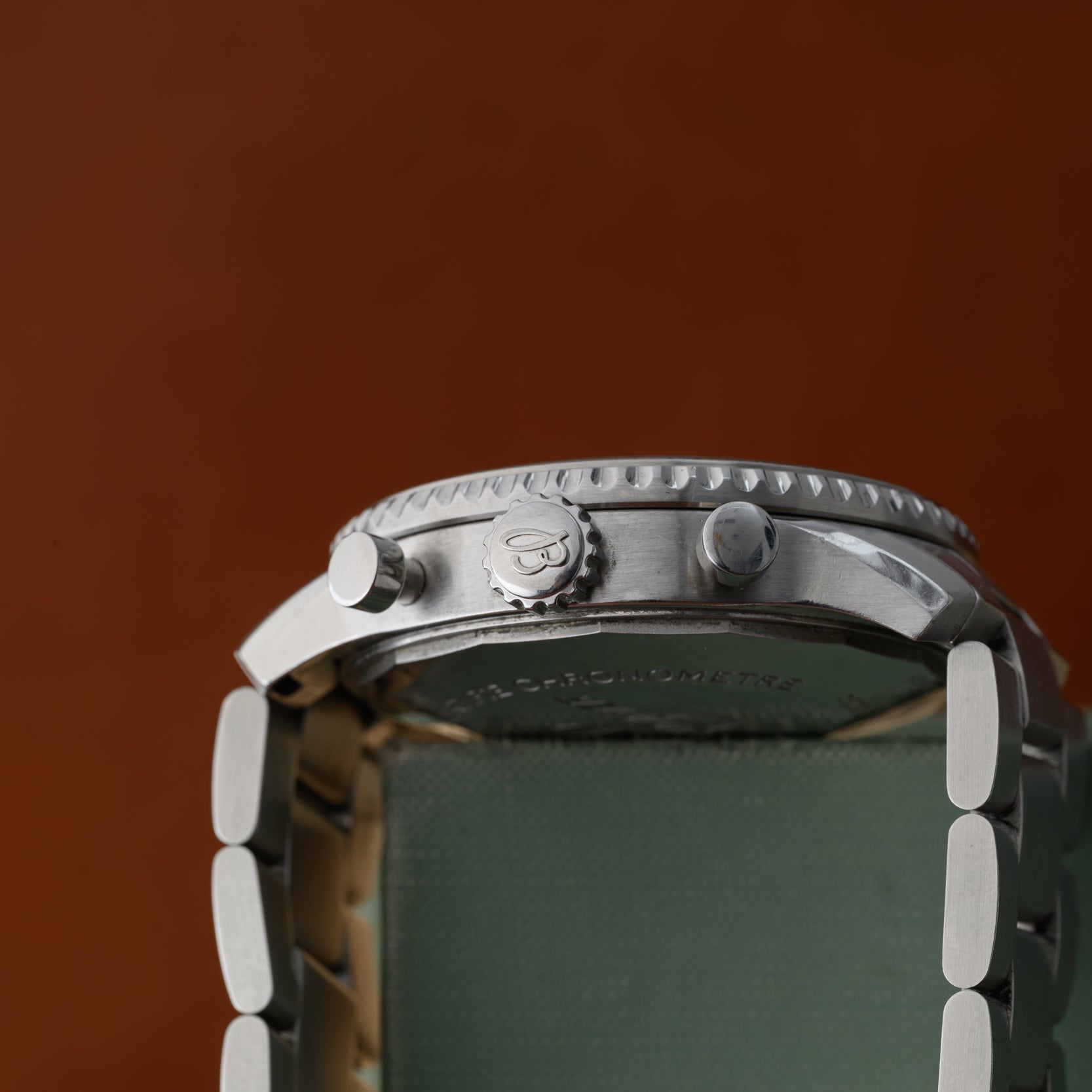 Side view of the Breitling Navitimer 8 Chronograph silver wristwatch with visible crown and pushers against a brown background.