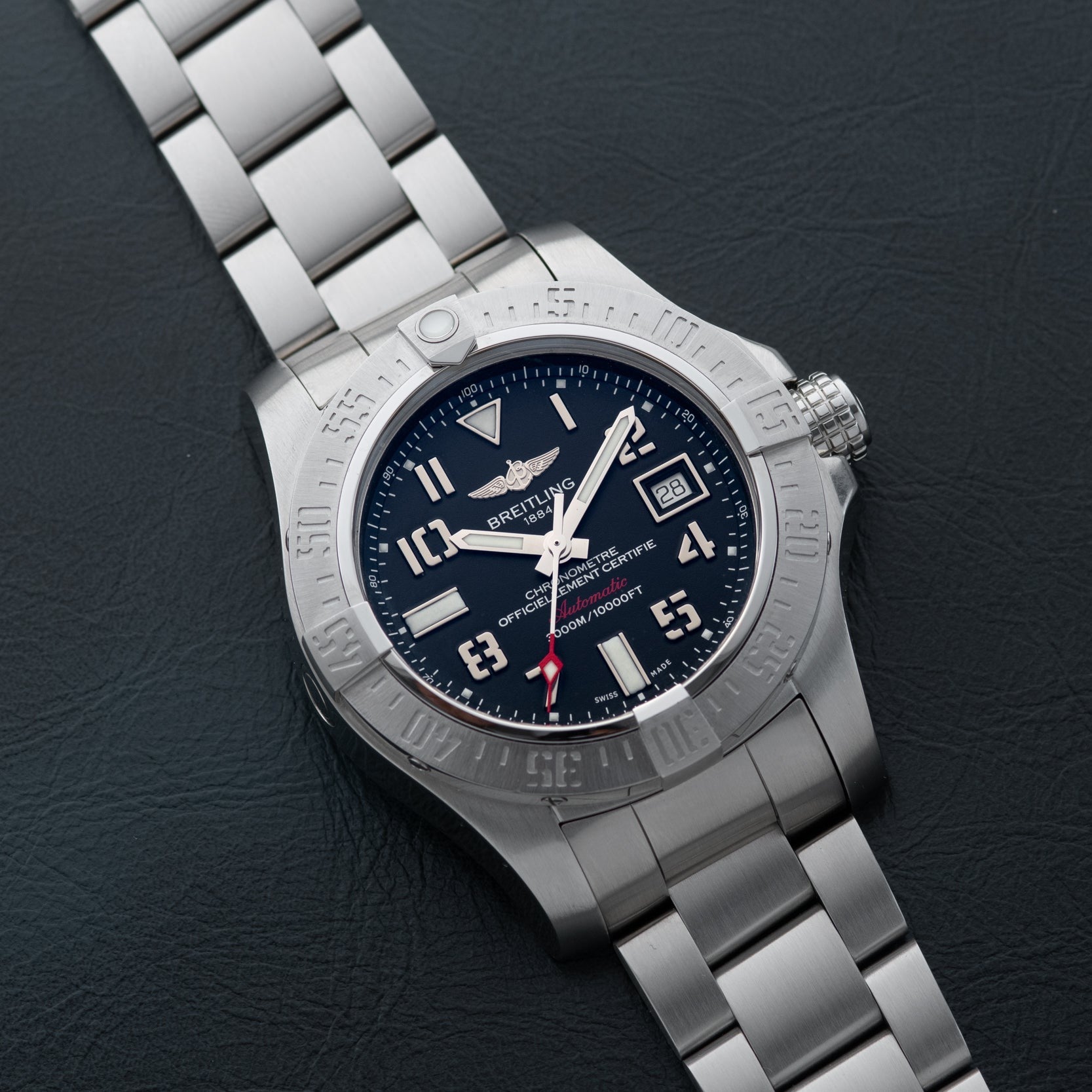 A Breitling Avenger II Seawolf with a stainless steel case, blue dial, and metal bracelet rests on a black surface.
