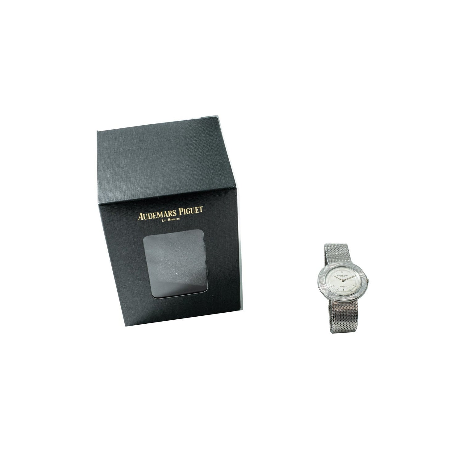 A silver Audemars Piguet Signed Disco Volante Dress Watch Gübelin is shown beside its black box with a clear display window.