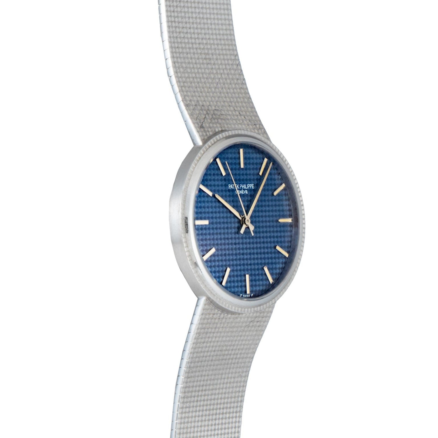 The Patek Philippe Calatrava Backwind is a silver wristwatch with a textured band and a blue, patterned face featuring silver hour markers.