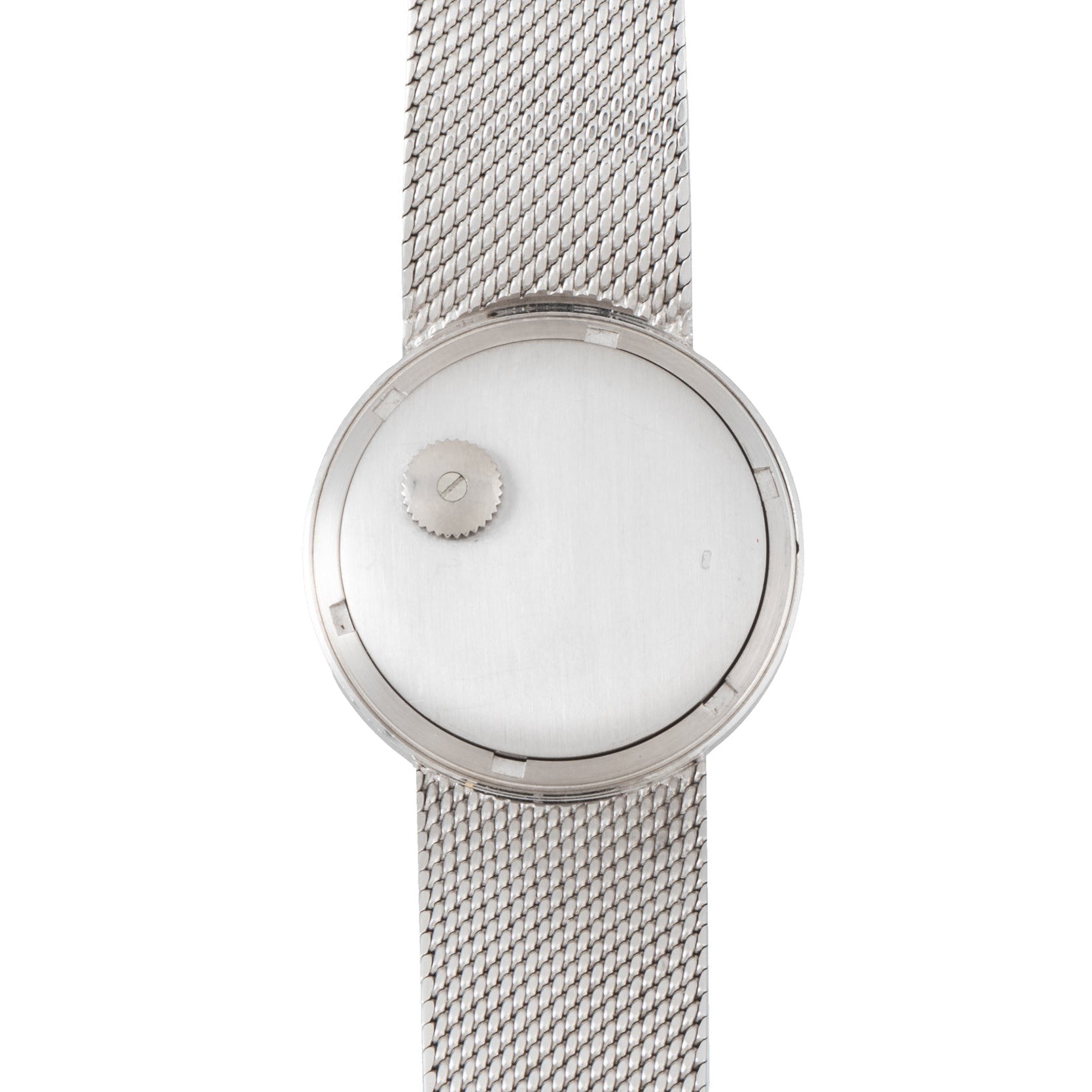 The Patek Philippe Calatrava Backwind is a minimalist silver wristwatch featuring a mesh band and a single off-center crown on its blank dial.
