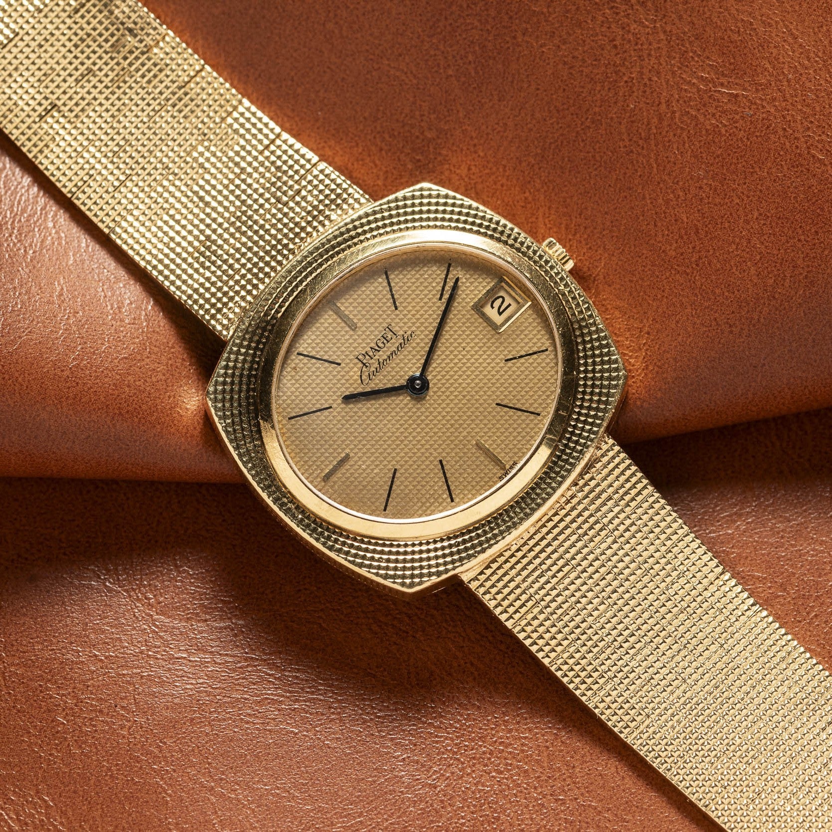 Yellow Gold Hobnail Dress Watch by Piaget featuring a minimal dial and date window on a brown leather strap.